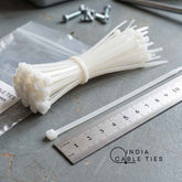 Bunch of white cable ties on a metal surface with a ruler and &